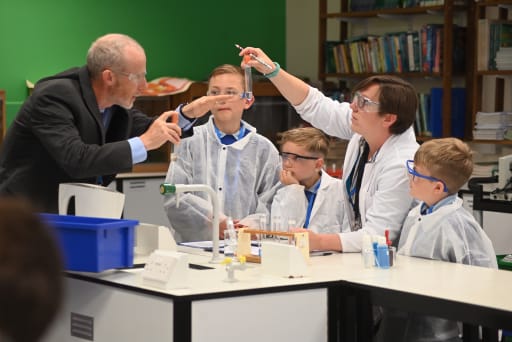 three children with two teachers doing science experiments