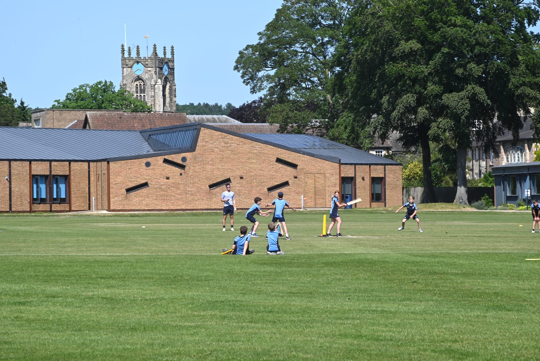 boys and girls playing cricket at Pocklington School with Pocklington All Saints' Church in background