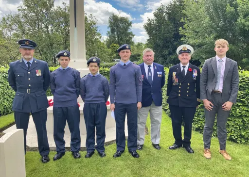 three adults and four children dressed in RAF uniform, stand infront of a war memorial