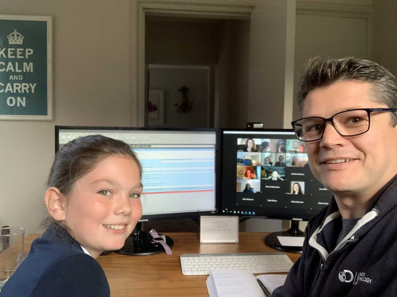 Girl and Father sitting next to a zoom call on computer