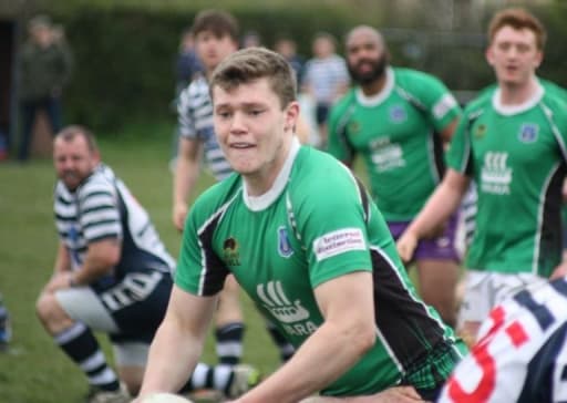 rugby player in green kit playing rugby on he pitch