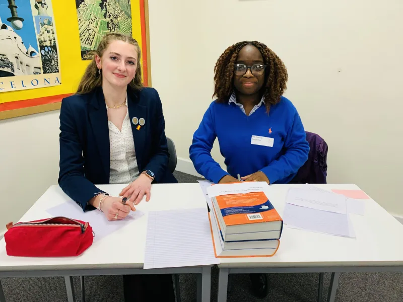 Two students sat at a desk in a classroom