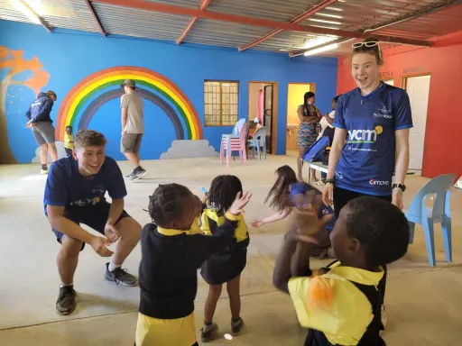 2 expedition team members interacting with children in a nursery classroom