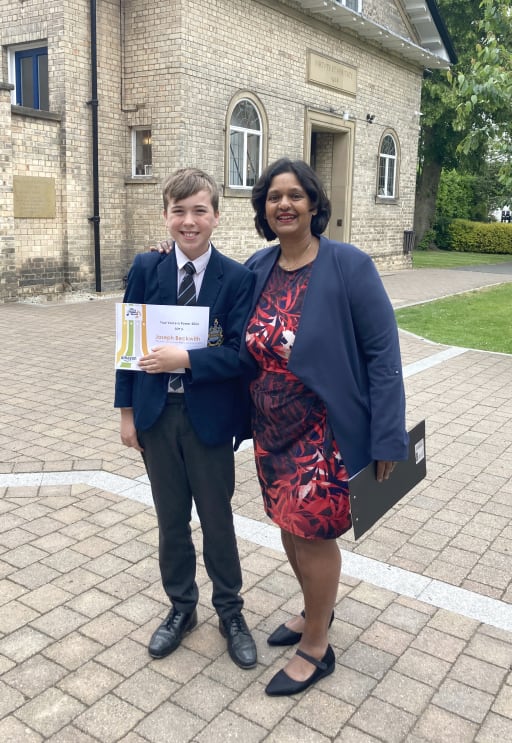 teacher and pupil holding a certificate in the grounds of Pocklington School