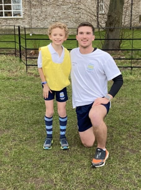 Pupil and teacher in sports kit posing for photo on grass