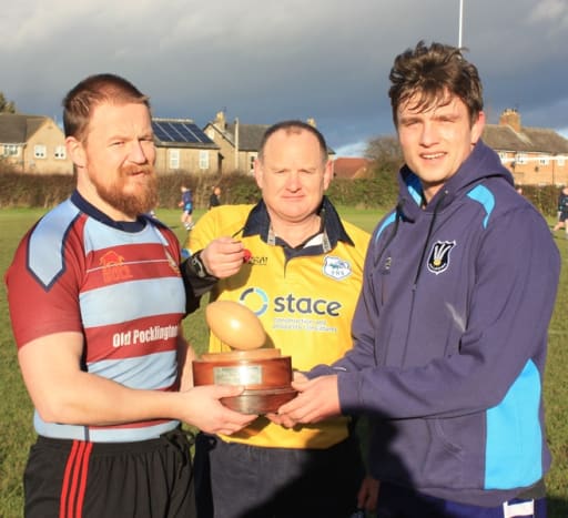 Captains from the two teams and referee hold the Bottomley Trophy