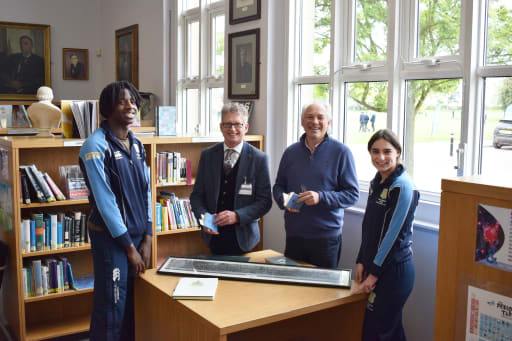 Current and former students of Pocklington School look at archive photograph in school library