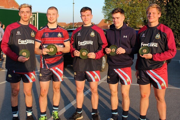 Five members of the Old Pocklingtoninan Pock 7s team stand holding green runner up plates in the car park of Pocklinton Twon Rugby Club