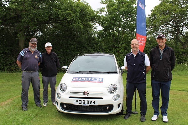 Four golfers stand with a white Fiat 500 car on the golf course at The Oaks Golf Course