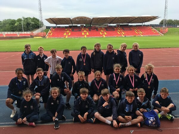 Pupils dressed in sports wear sit on running track at the Gateshead International Stadium where they competed in the HMC Athletics North East meeting.