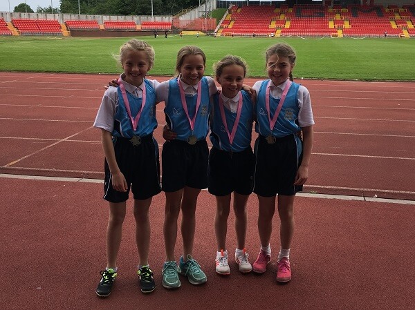 Pocklington Prep School girls U10 4 x100m relay team stood on running track at Gateshead International Stadium