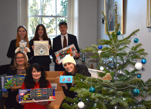 Students, teachers and YorkMix radio presenter, stand next to Christmas tree holding gifts donated to the Toy Appeal 