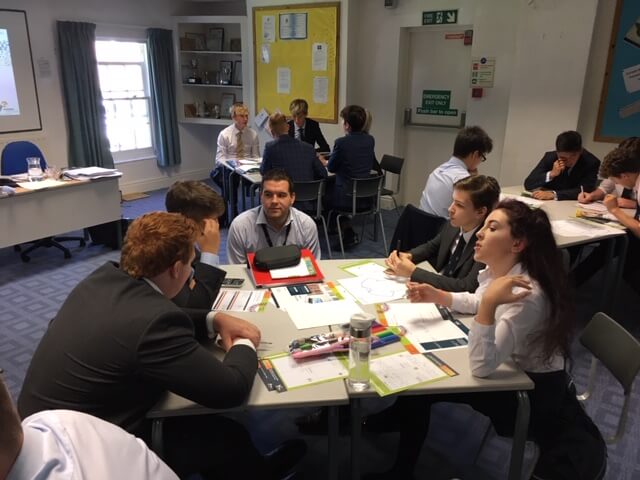 Business man talks with A level Business students in a classroom