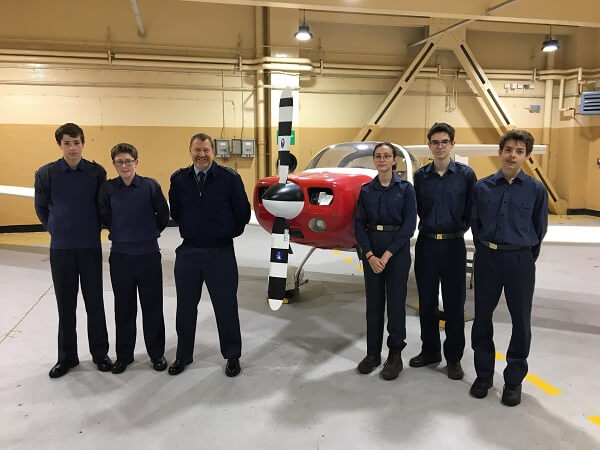 Uniformed CCF cadets and instructor stood in front of training aeroplane at RAF Topcliffe 