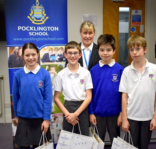 Four primary school children holding their prizes after winning the Maths Challenge, stood with Head of Maths teacher from Pocklington School