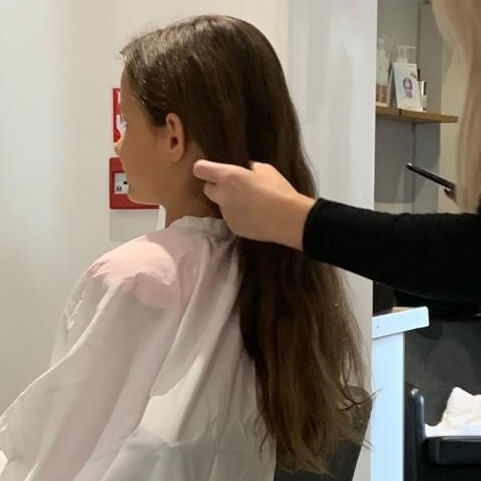 Hannah sits in hairdressers chair at Mark Lee Hairdressing before having her long locks cut for donation to the Little Princess Trust