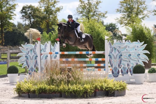 pony and rider attempting show jump in outdoor arena