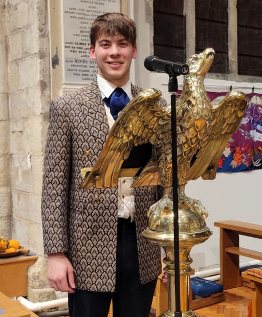 Pupil dressed in period clothing stands at lectern in All Saints' Church Pocklington