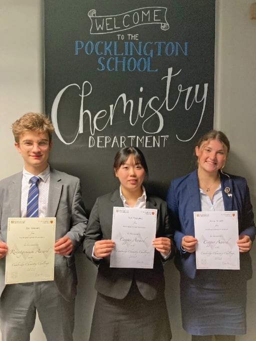 3 chemistry students holding award certificates outside Pocklington School chemistry labs