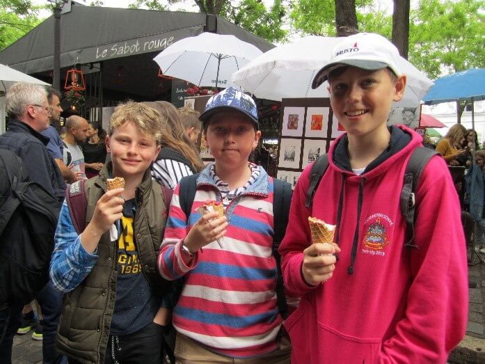 three boys stood holding icecreams in Montmartre, Paris