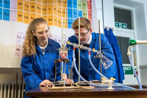 Two Pocklington School pupils looking at apparatus set up for an experiment in a school lab