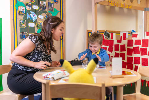 teacher watching a pre-school boy play at a table