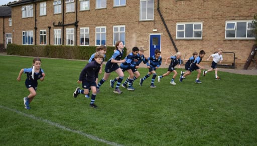 Group of children wearing sports kit and running on a school field