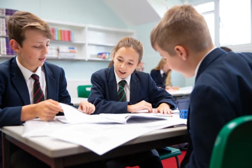 Two boys and a girl sat at a desk, working in a classroom at Pocklington School