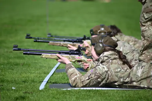 CCF cadets outside, laid on grass holding air rifles