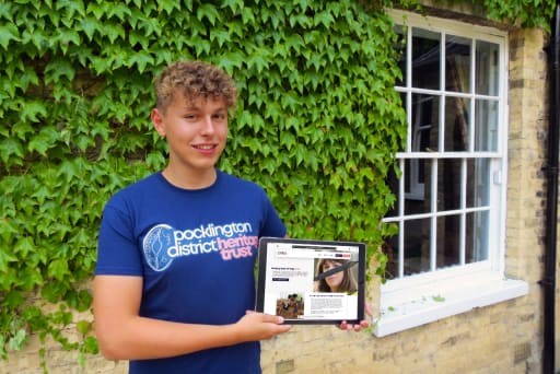 Pocklington School pupil holding ipad displaying new logo for District Heritage Trust Logo he designed