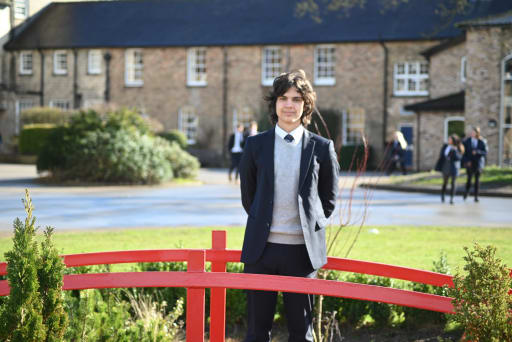 Pocklington School student standing in school grounds on a red bridge