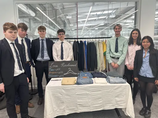 Seven students stood behind a table, displaying their business idea