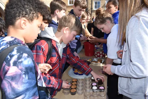 group of children buying cakes at a stall in the school playground