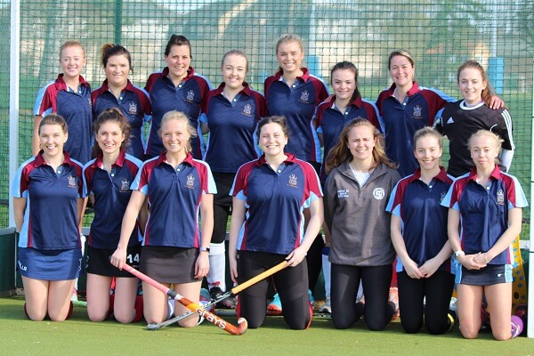 Old Pocklingtonian Ladies' Hockey team kneeling in the goal mouth of the hockey pitch