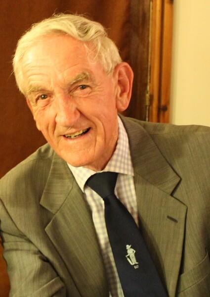 Malcolm Milne, OP and Former Teacher at Pocklington School wearing suit and tie with Pixie emblem