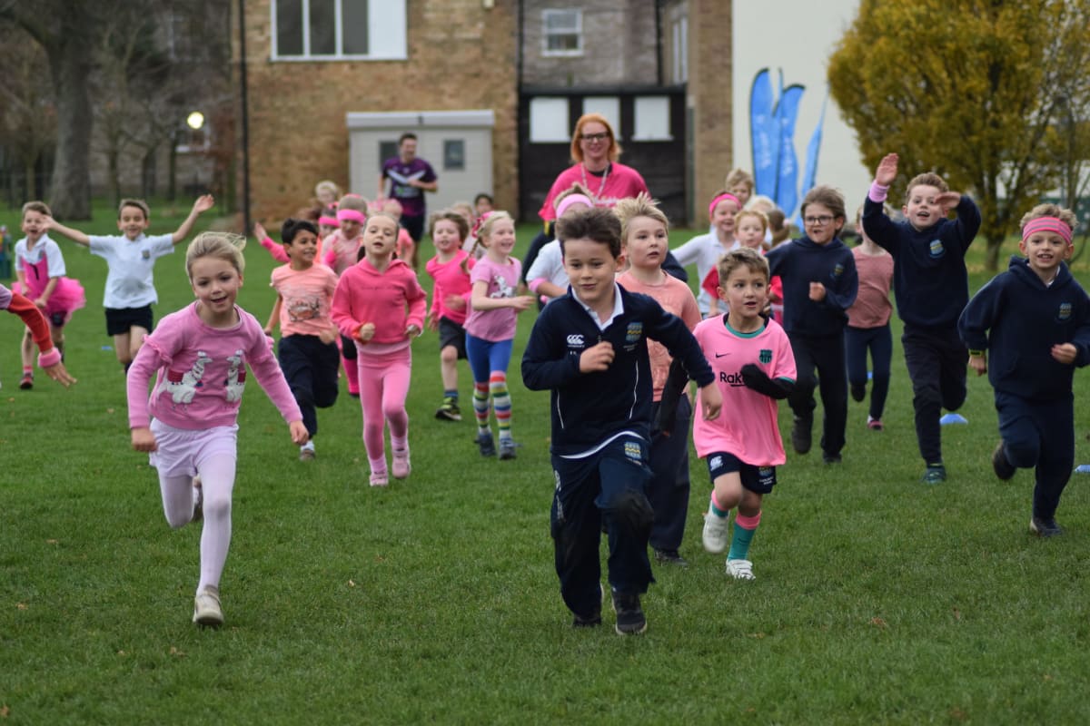 Children and teachers running on the school field during the Pock Prep Run