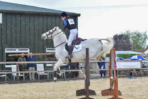 rider and pony mid jump an equestrian arena