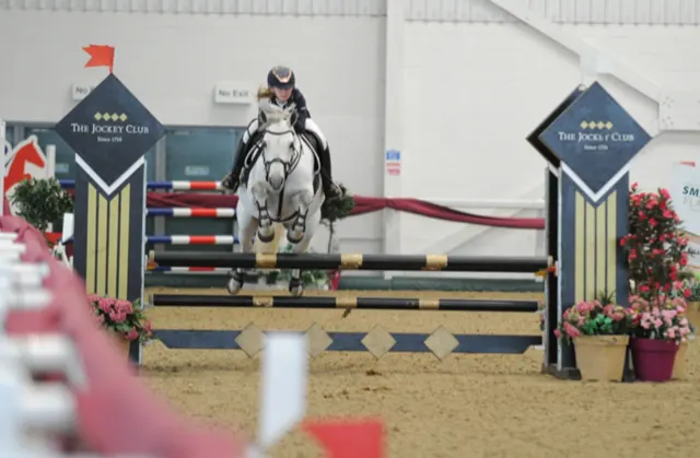 Rider and pony mid jump in the British Showjumping Indoor Championships 2020