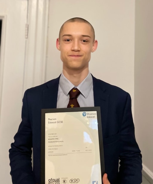 pupil holding framed GCSE examination certificate