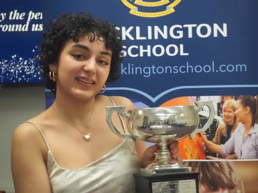 Winner of Lectern Society 2024 holding trophy stood in front of Pocklington School banner