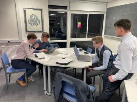 4 maths students sat round table, solving maths calculations