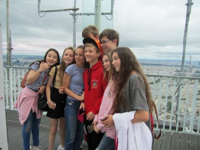 group of children stood on the glass walled viewing deck of the Montparnasse Tower