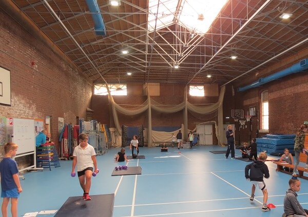 Children exercising using gym equipment in Pocklington School sports hall as part of a strength and conditioning masterclass