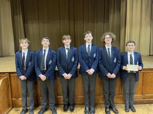 6 Pocklington School pupils in school uniform stood in front of a school stage