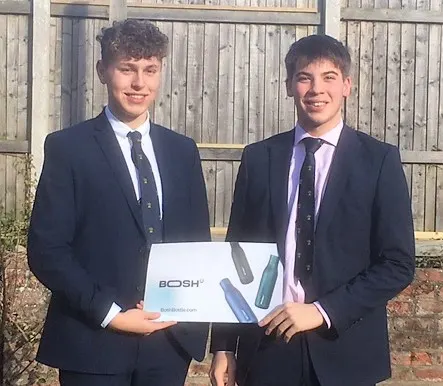 Two pupils from Young Enterprise team holding poster showing their company logo,Bosh Bottle